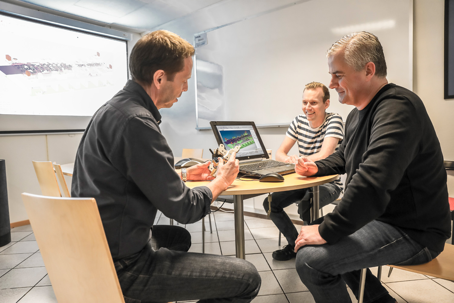 Tre personer sitter vid ett bord och granskar ett verktyg